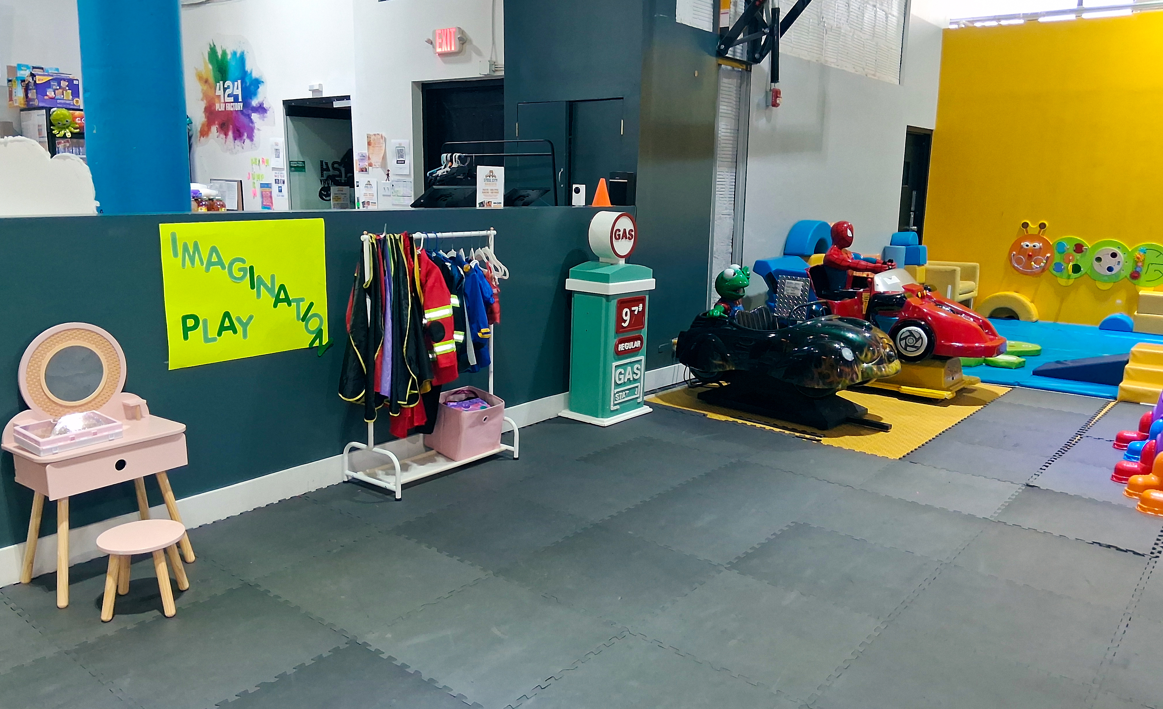 Imagination Play zone at 424 Play Factory, featuring dress up costumes, car ride-ons, and other fun toys.